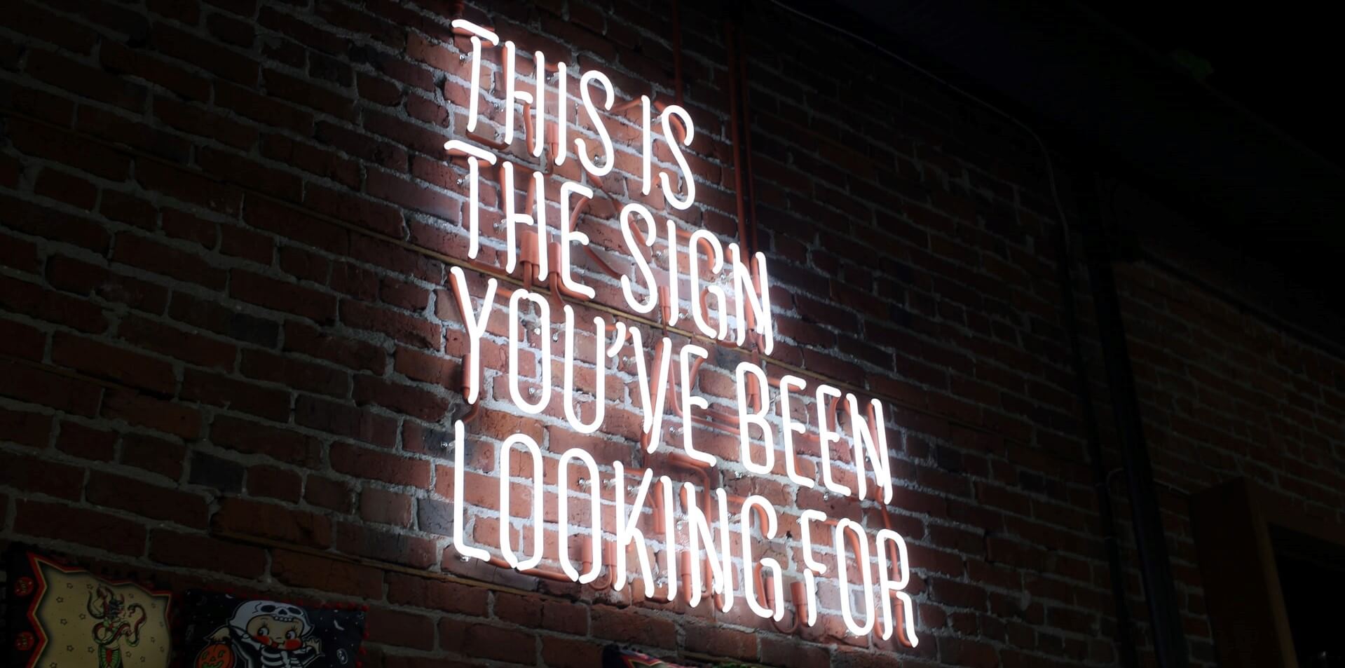 "This is the sign you've been looking for" white neon sign on brick wall