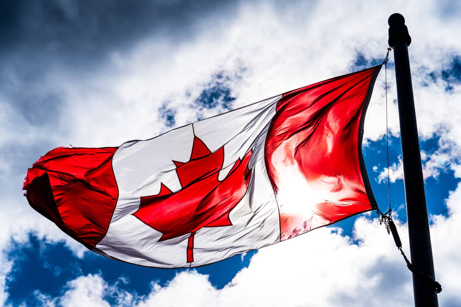 Canadian flag against blue sky and white clouds