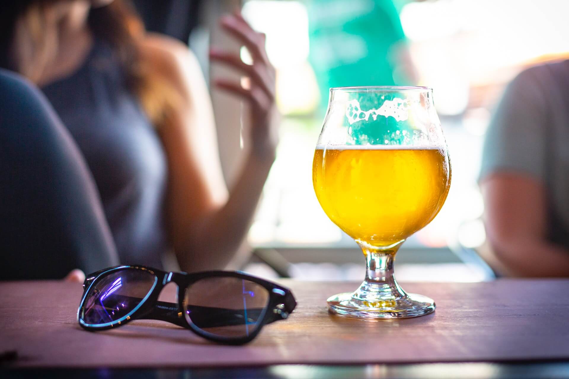 Sunglasses and beer on table at a bar