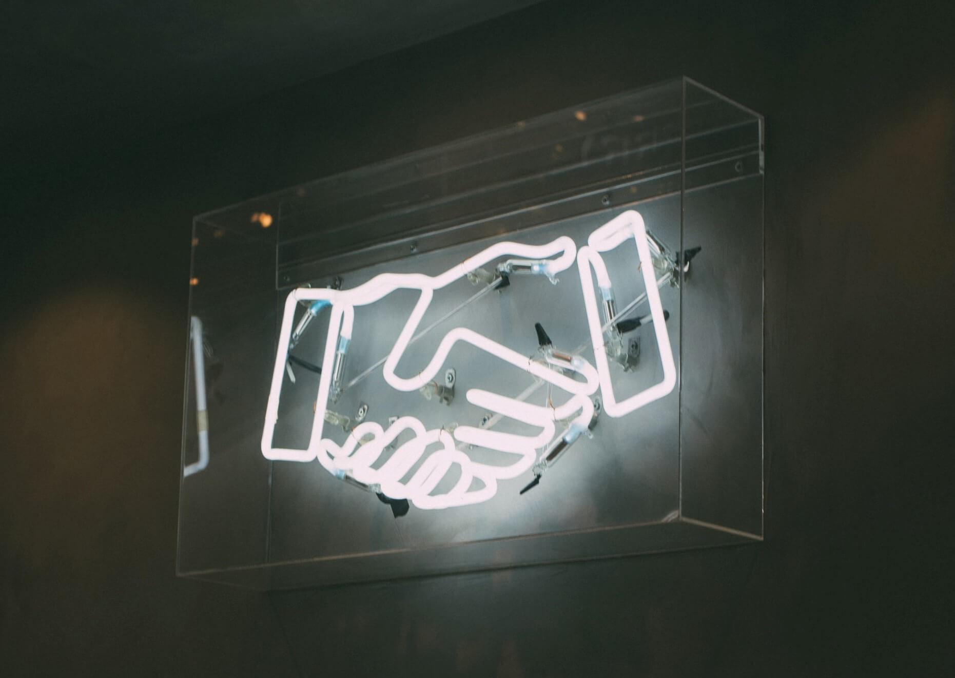 Handshake emoji neon sign signifying partnership