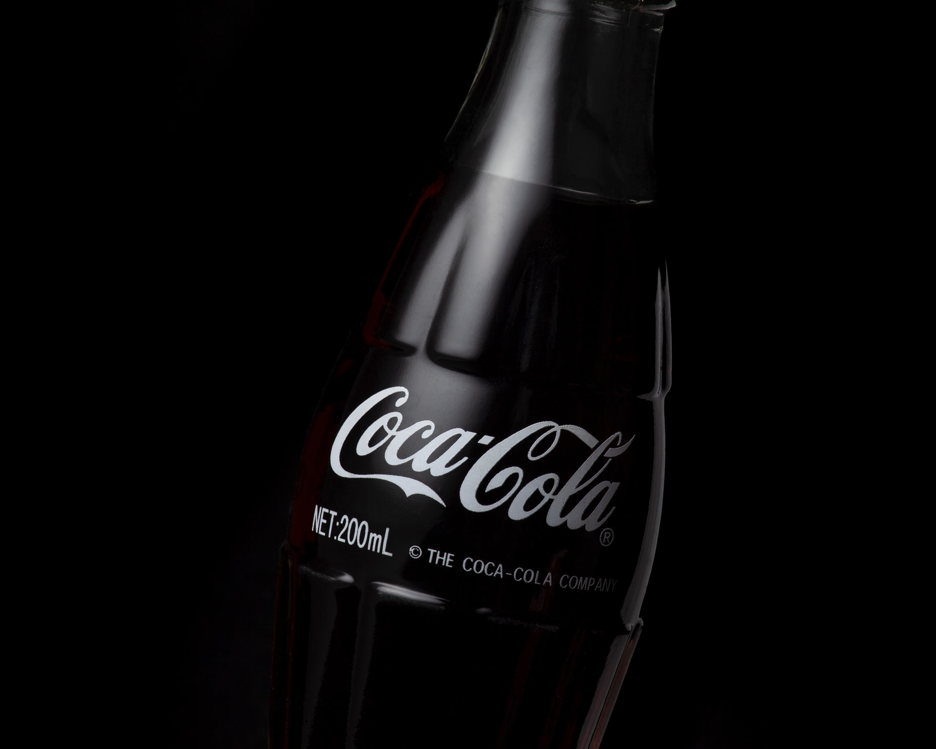Black glass Coca-Cola bottle with black background