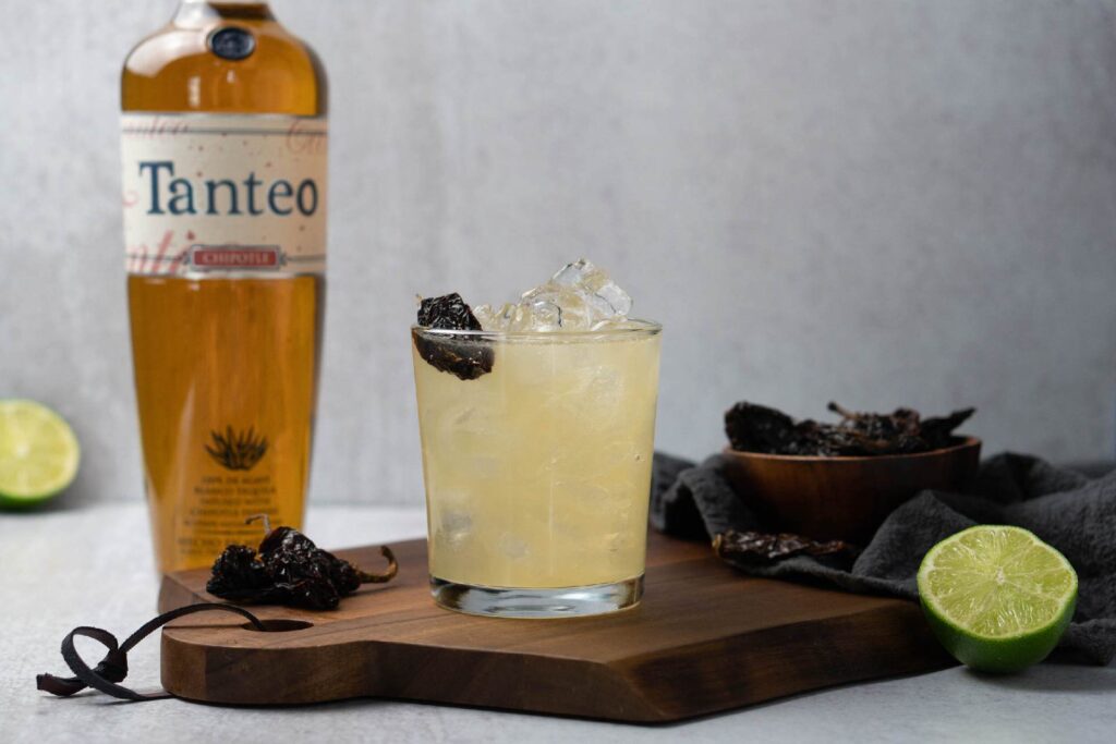 Tanteo Chipotle Margarita in garnished rocks glass next to tequila bottle