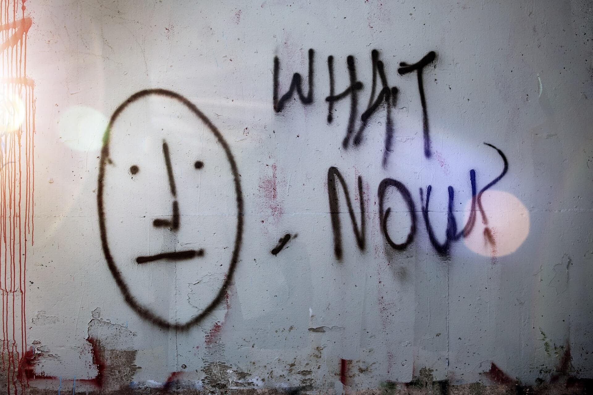 "What Now?" graffiti in black spray paint on wall