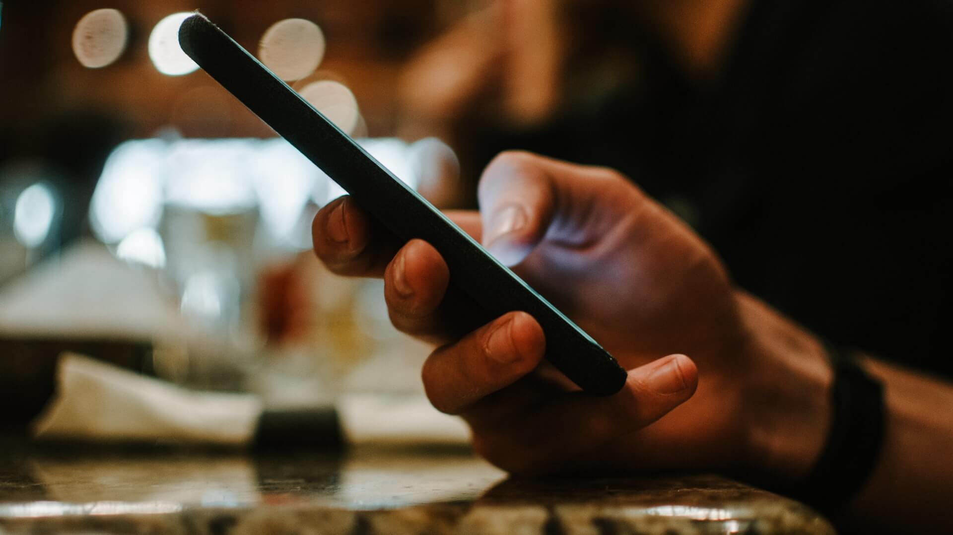 Close-up shot of person texting on phone in a restaurant