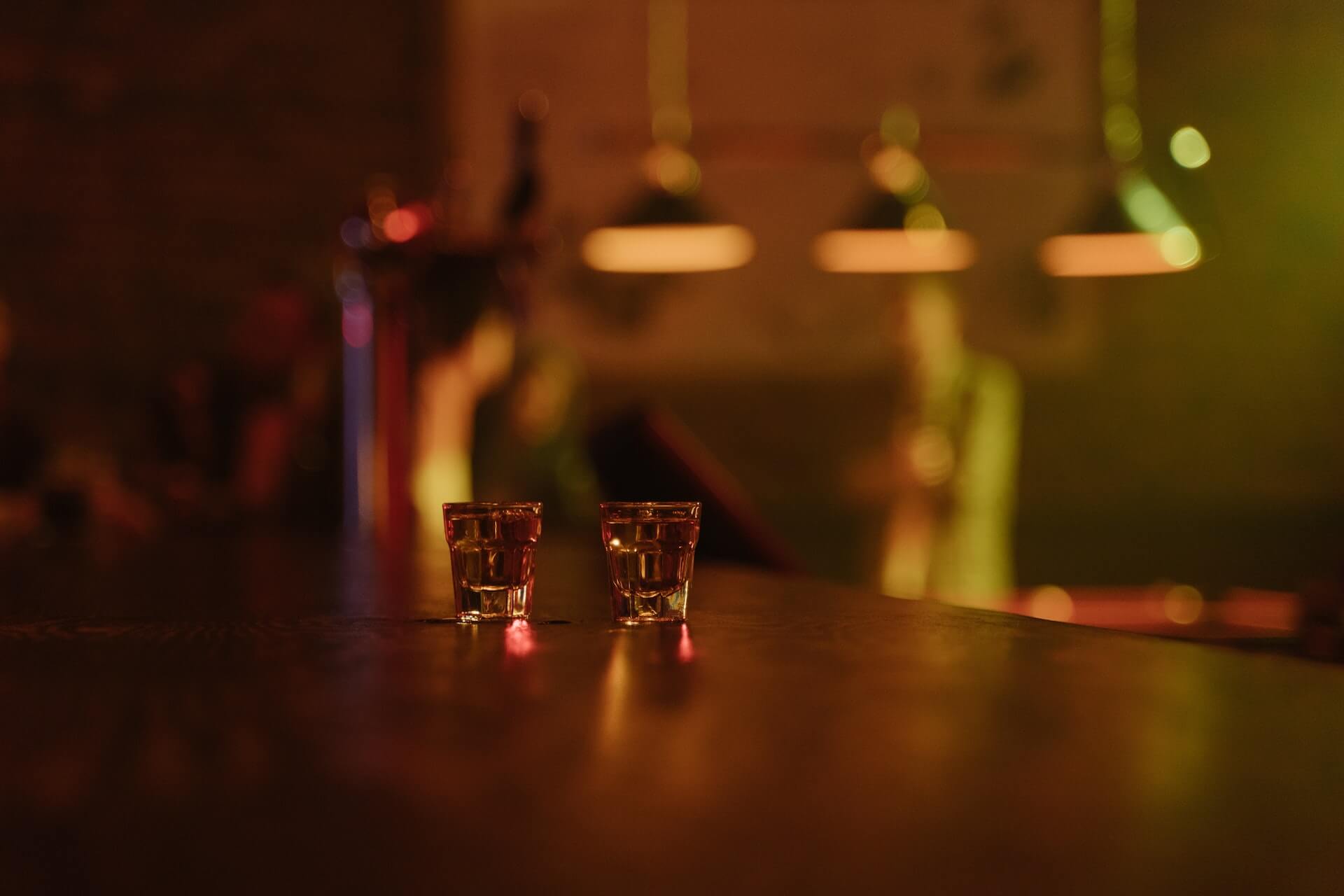 Two full shot glasses on a bar
