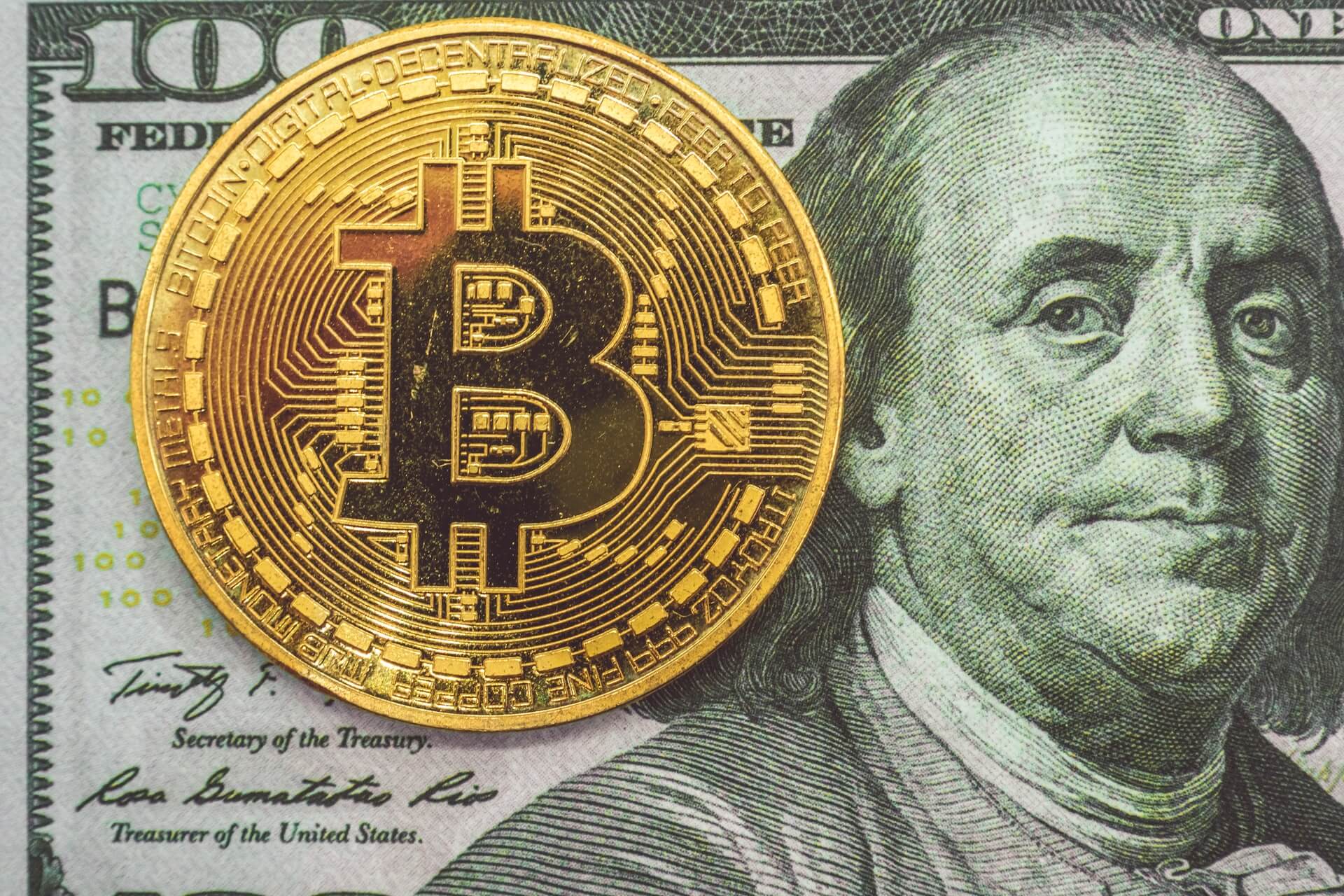 A Bitcoin on top of a $100 bill