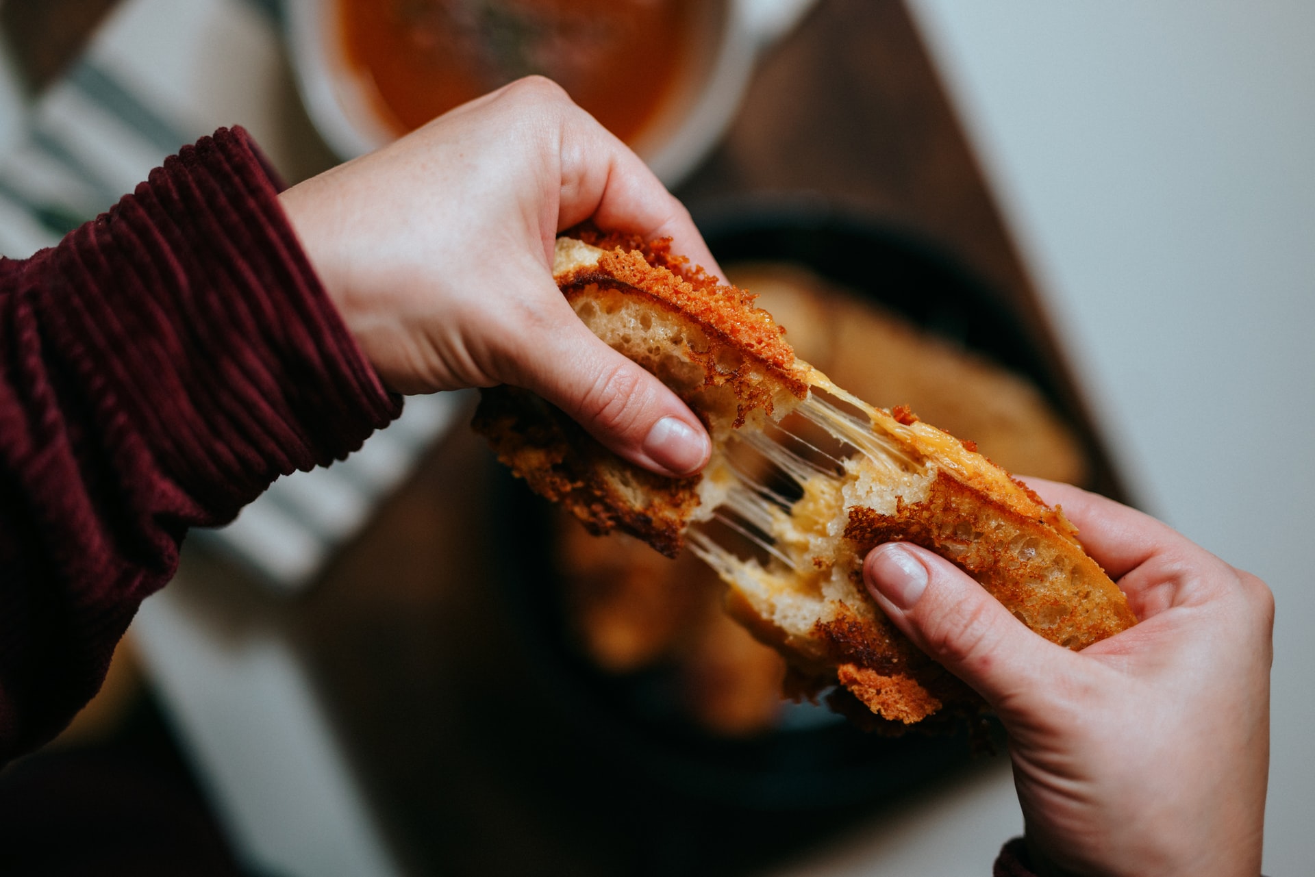 Person pulling apart melty grilled cheese sandwich