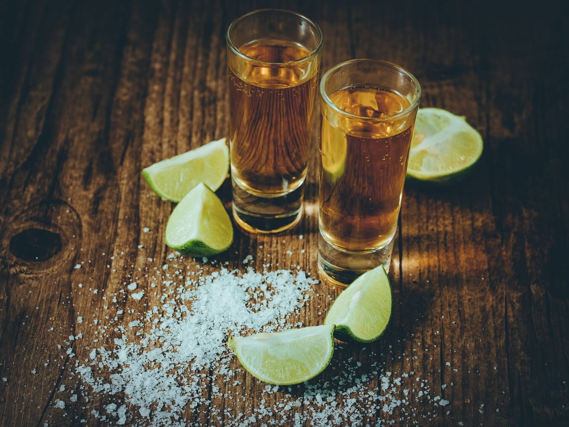 Shots of tequila surrounded by lime wedges and salt