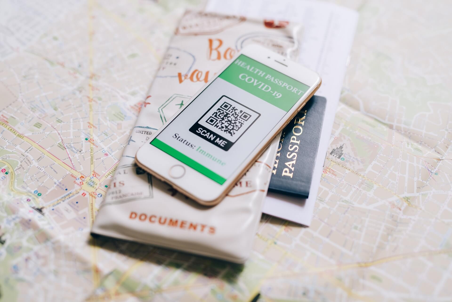 Vaccine passport on phone sitting on map and passport