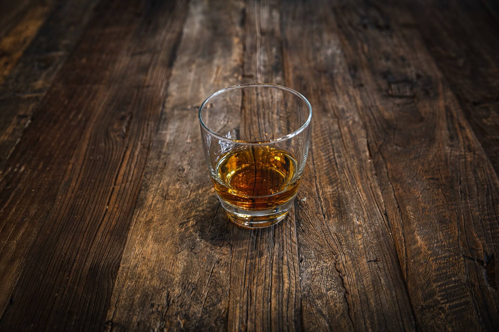 Shot of bourbon on wood background