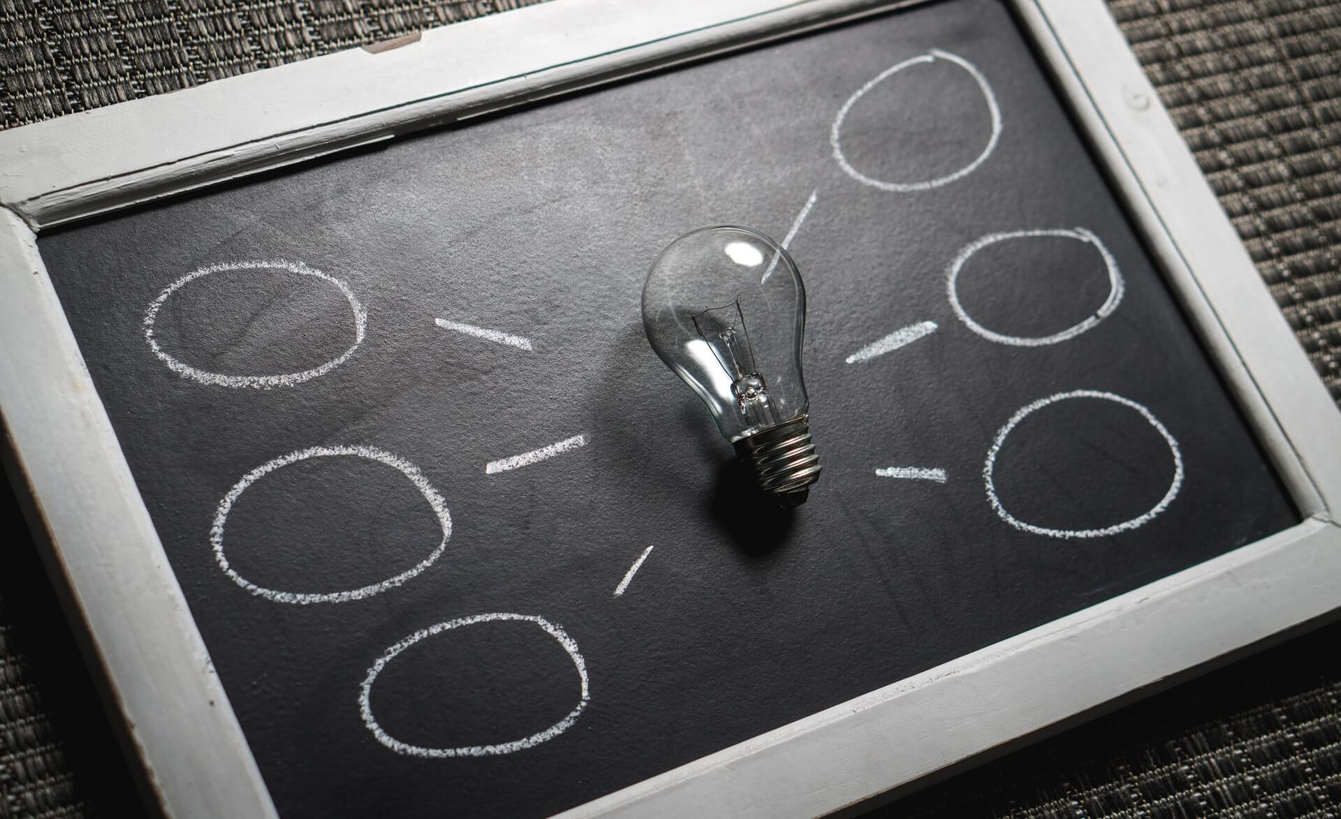 Thinking differently planning concept with light bulb on chalkboard