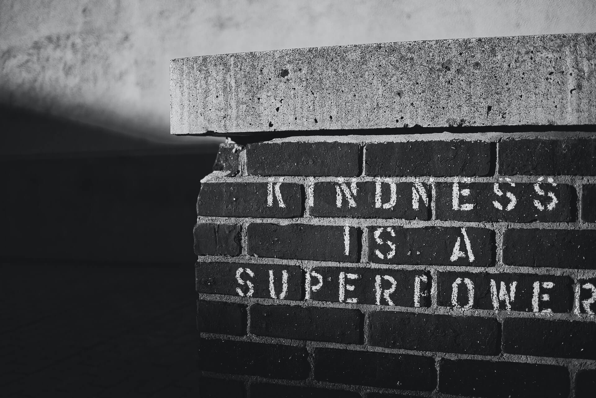 Kindness is a Superpower stencil graffiti on brick wall in black and white