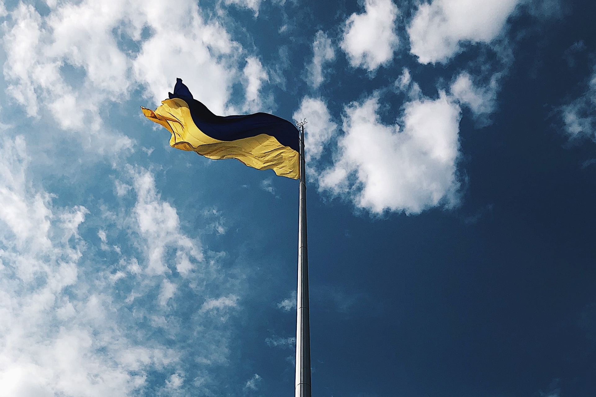 Ukraine flag flying against blue sky, perspective shot