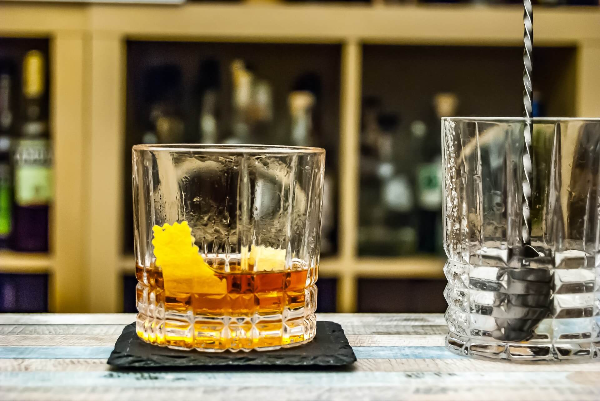 Sazerac cocktail and mixing glass on bar