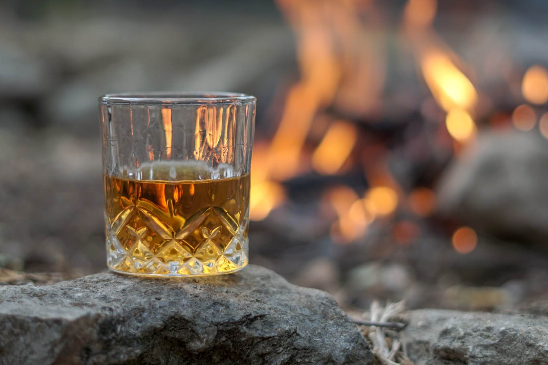 Glass of bourbon whiskey next to fire