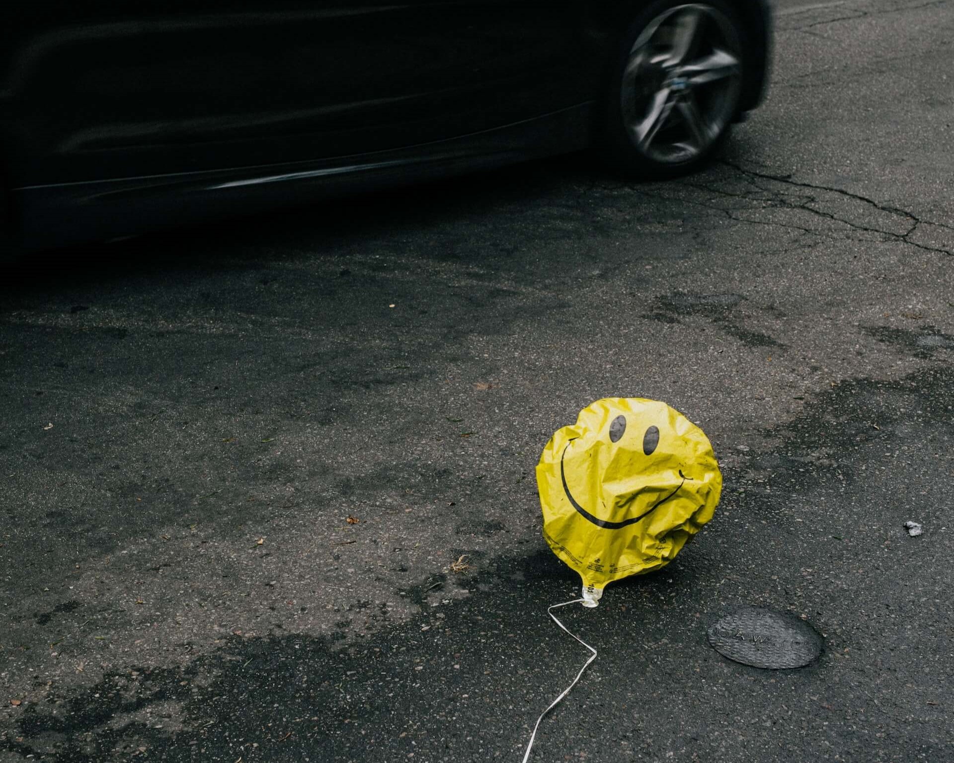 Deflated smiley face balloon in street