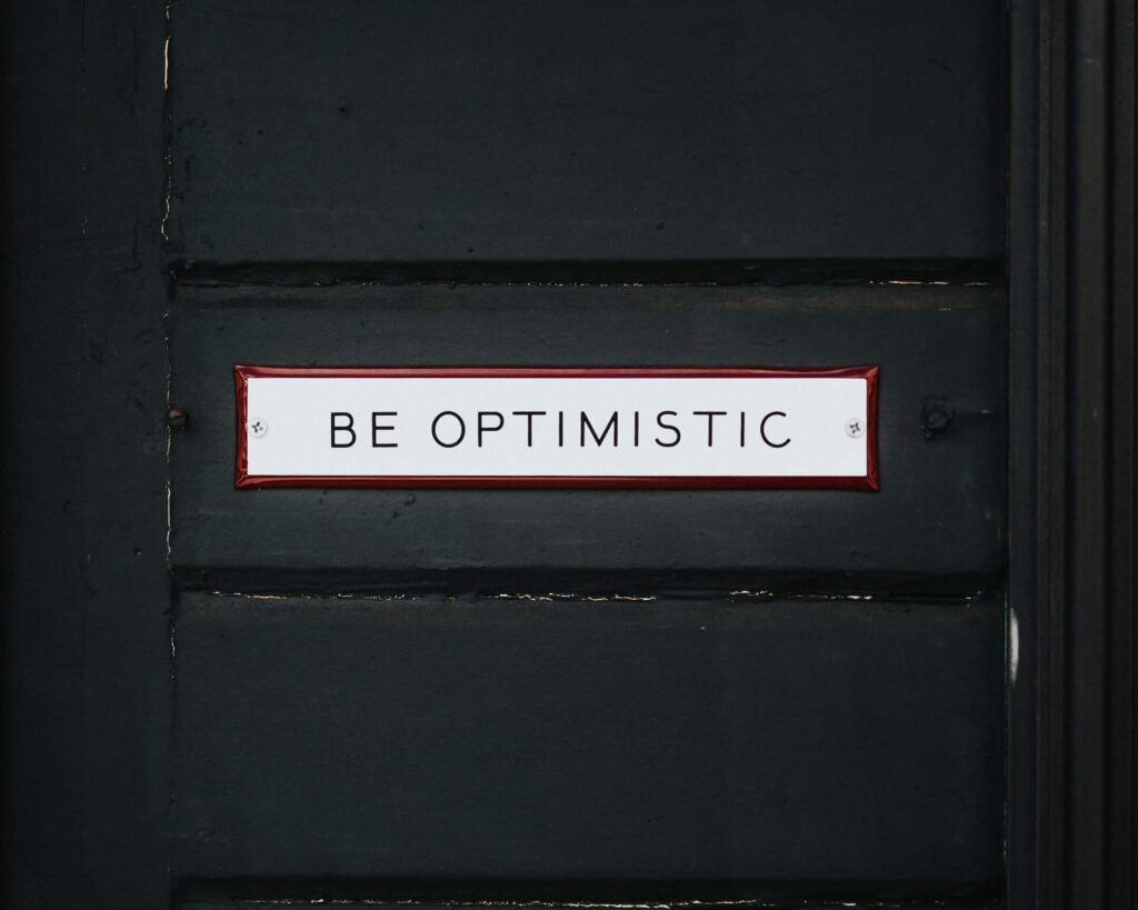 "Be optimistic" sign on black door