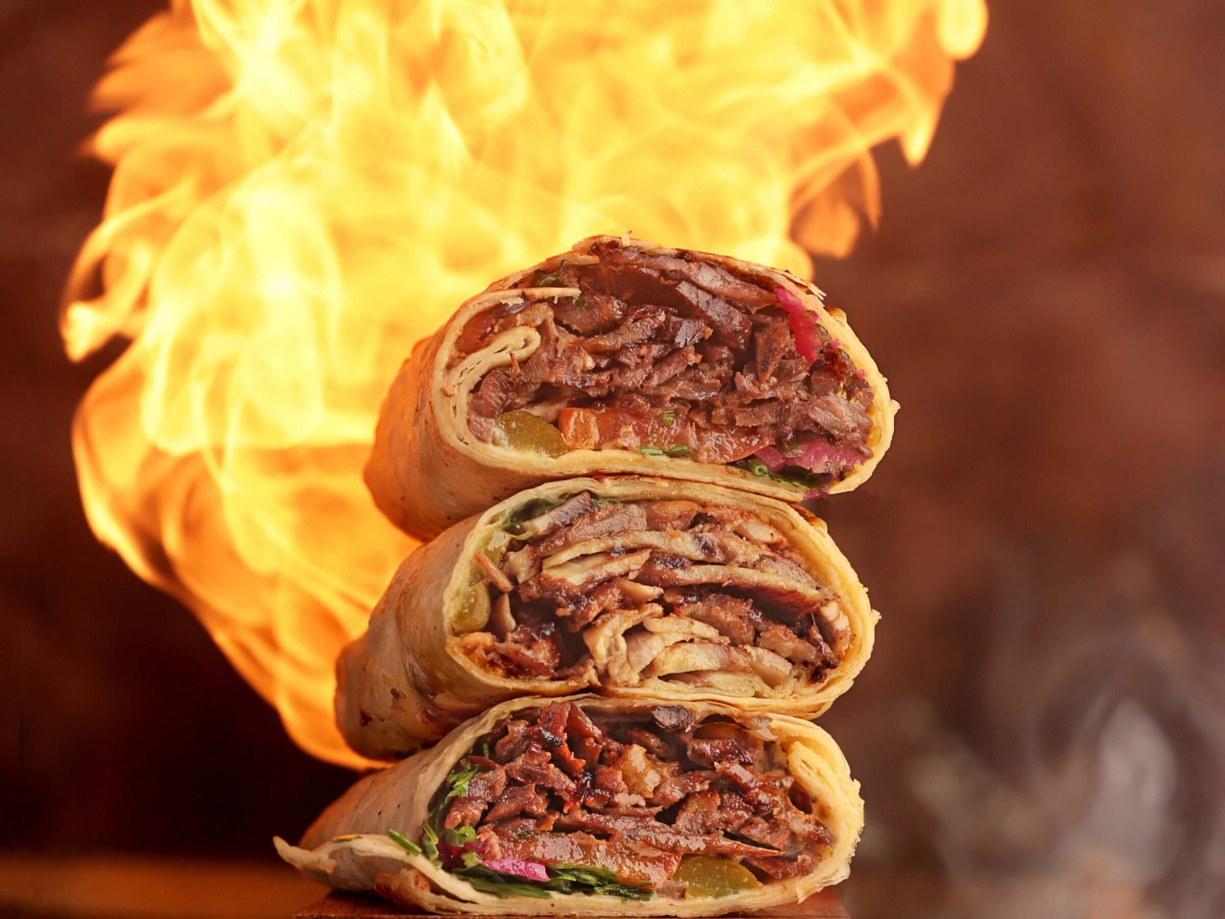 Shawarma stacked with fire in the background