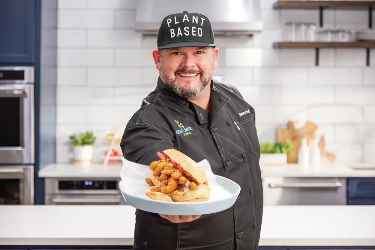 Chef Brian Duffy holding a plate with a plant-based shrimp po' boy sandwich on it