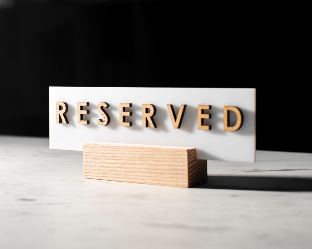 White "Reserved" sign in wooden block on table