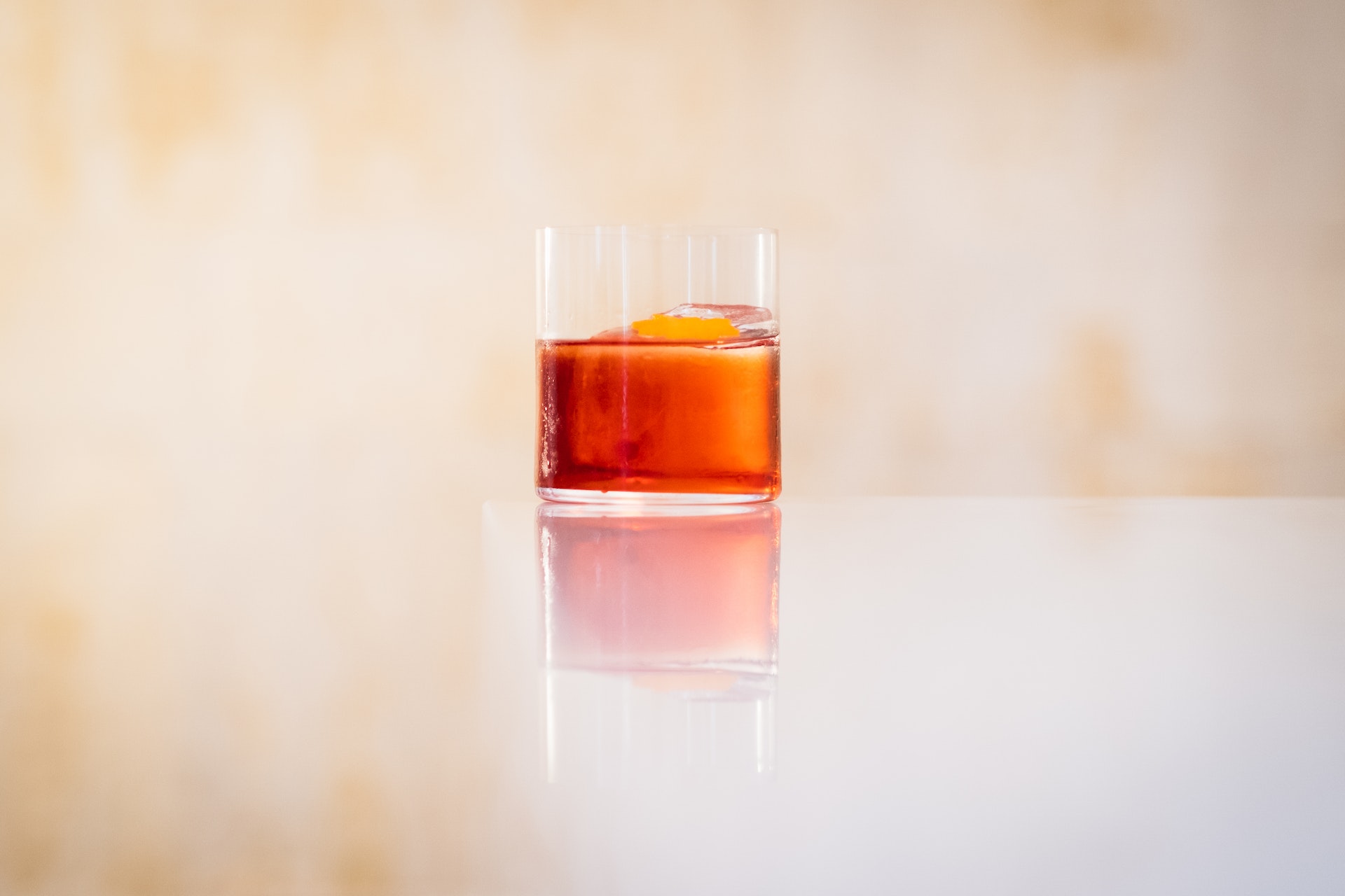 Negroni on edge of white countertop with reflection