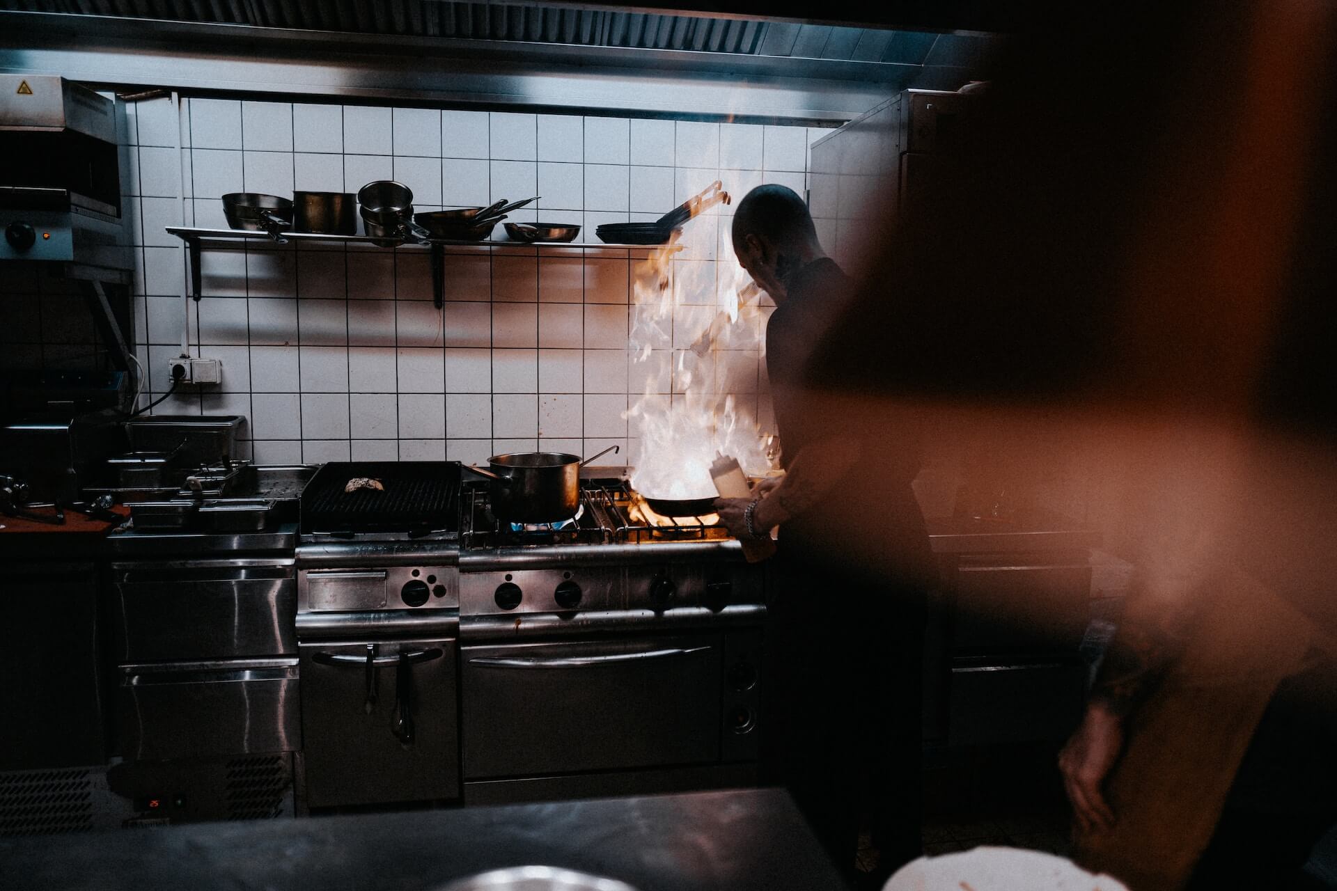 Chef handling flaming pan in commercial kitchen