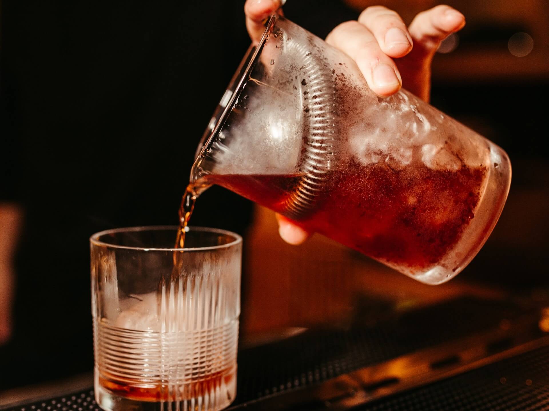 Bartender pouring Negroni into glass