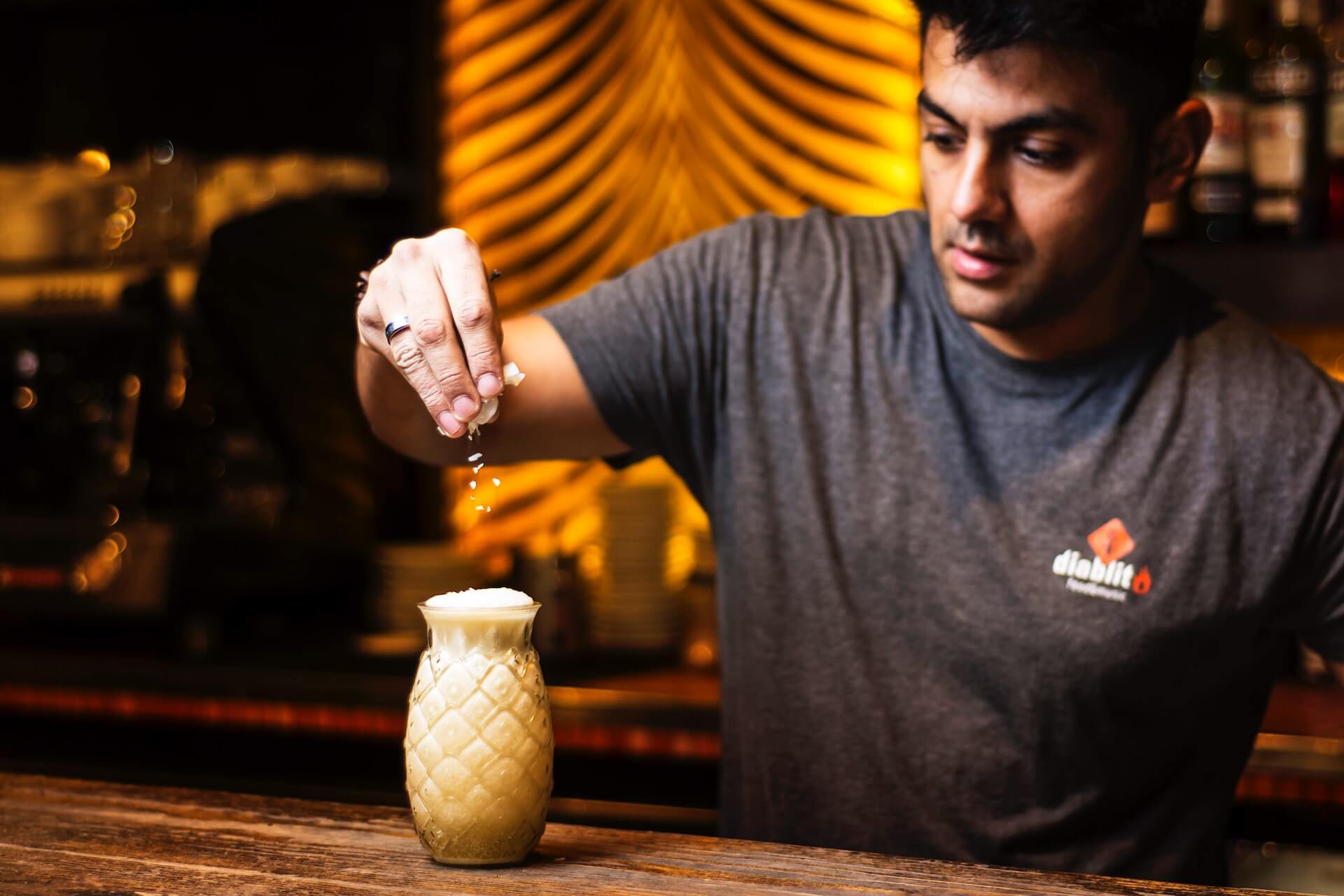 A bartender serving a cocktail in a pineapple-shaped glass