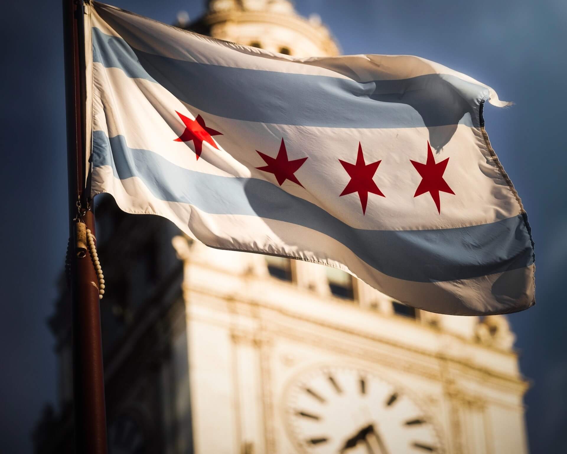 Closeup shot of the flag of the City of Chicago with Wrigley Building in background