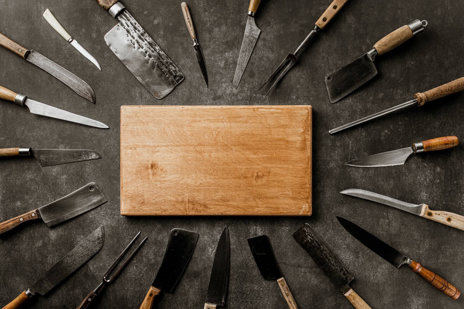 Collection of various vintage knives surrounding a cutting board