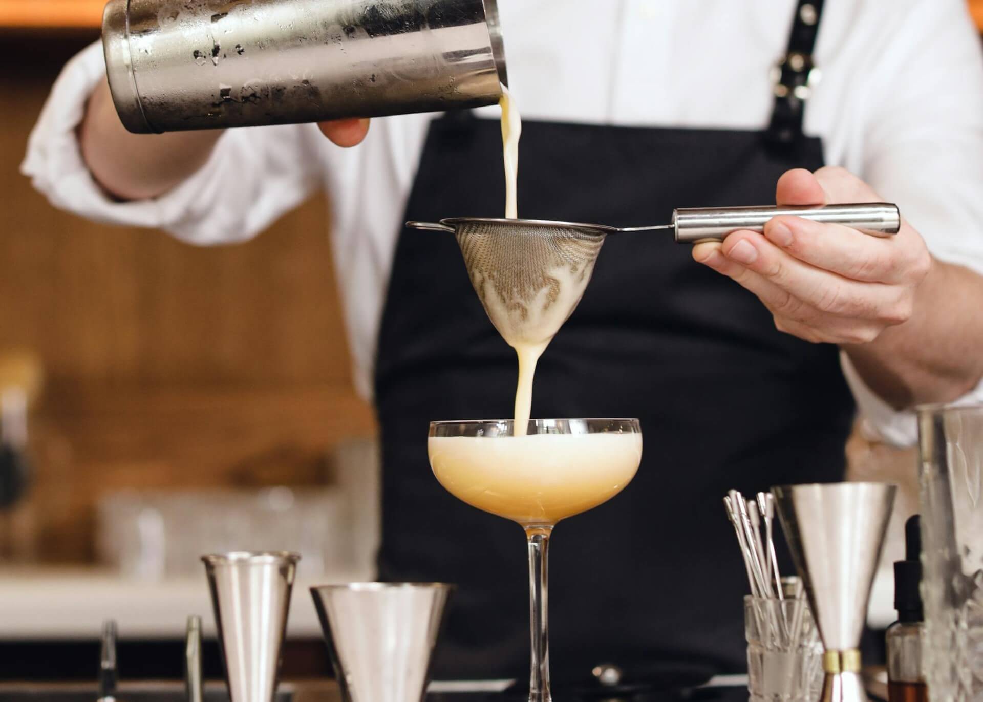 Bartender straining cocktail into glass