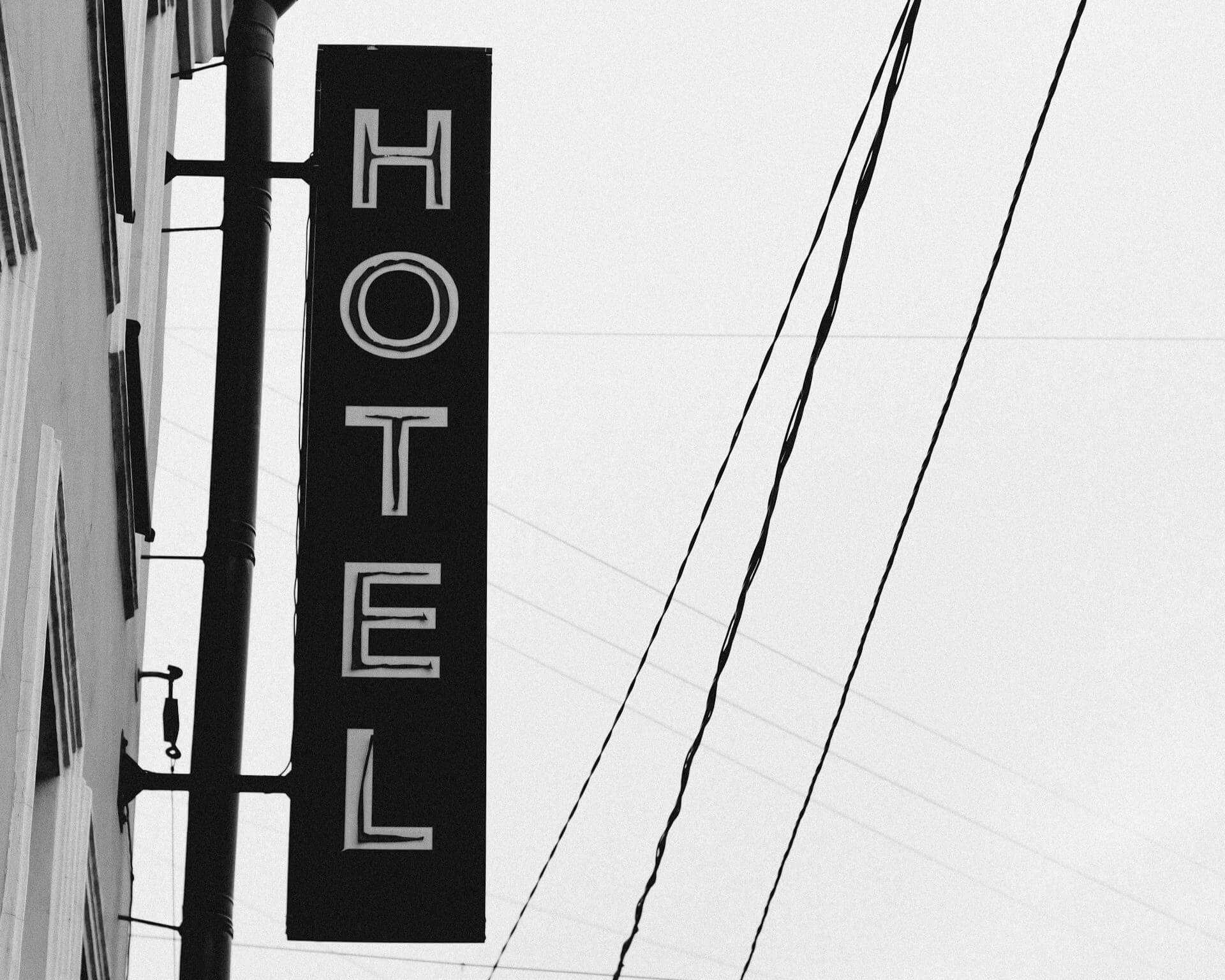 Black and white photo of hotel sign hanging vertically on hotel exterior