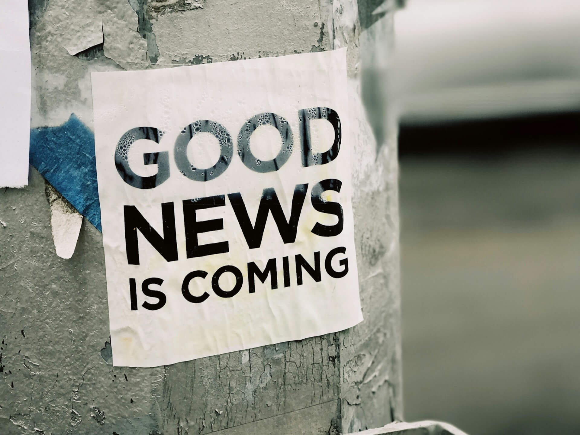 "Good news is coming" sign taped to a pole on the street