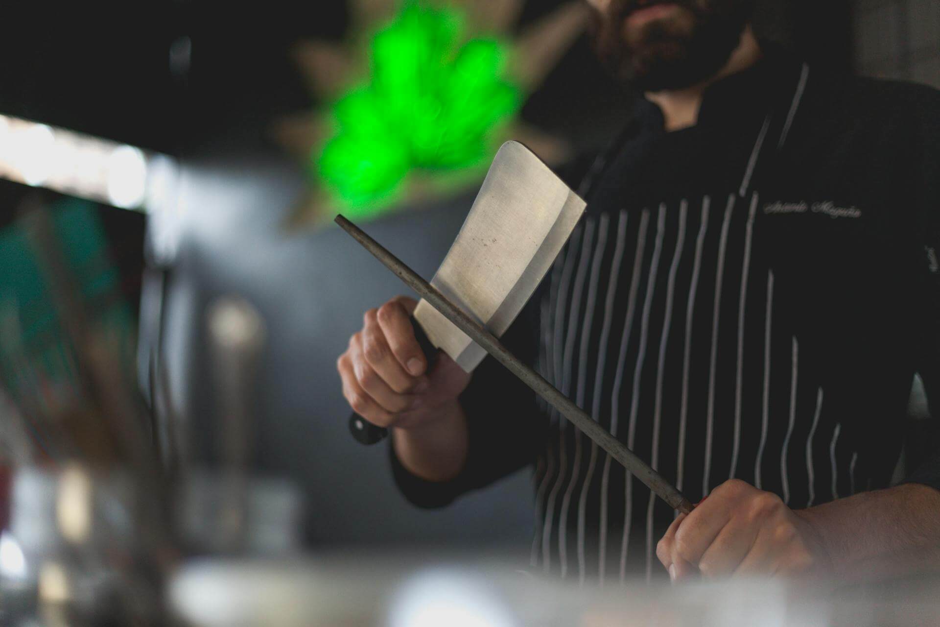 Close-up photograph of a chef sharpening a cleaver