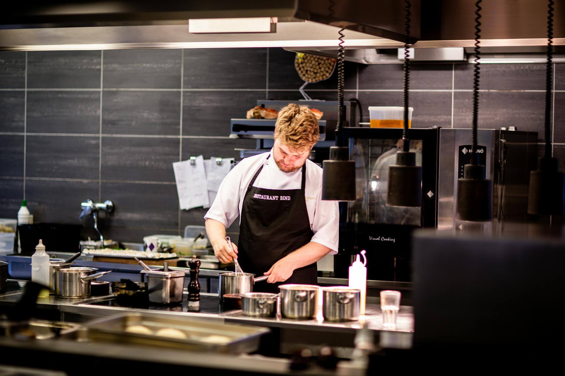 A young male chef preparing a dish in a clean, modern commercial kitchen