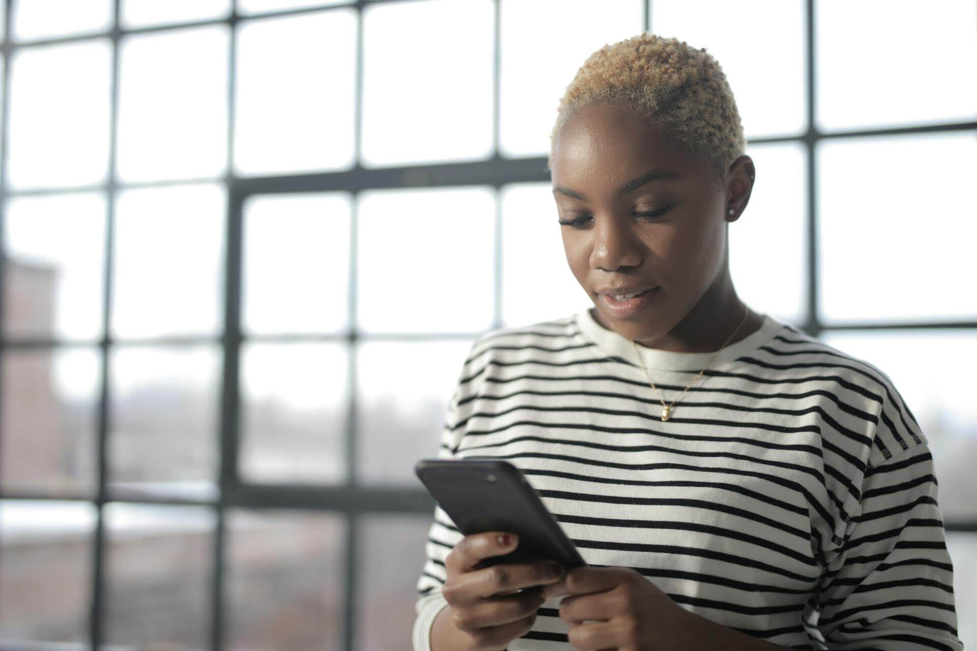 A woman wearing a black-and-white-striped top checking her smartphone