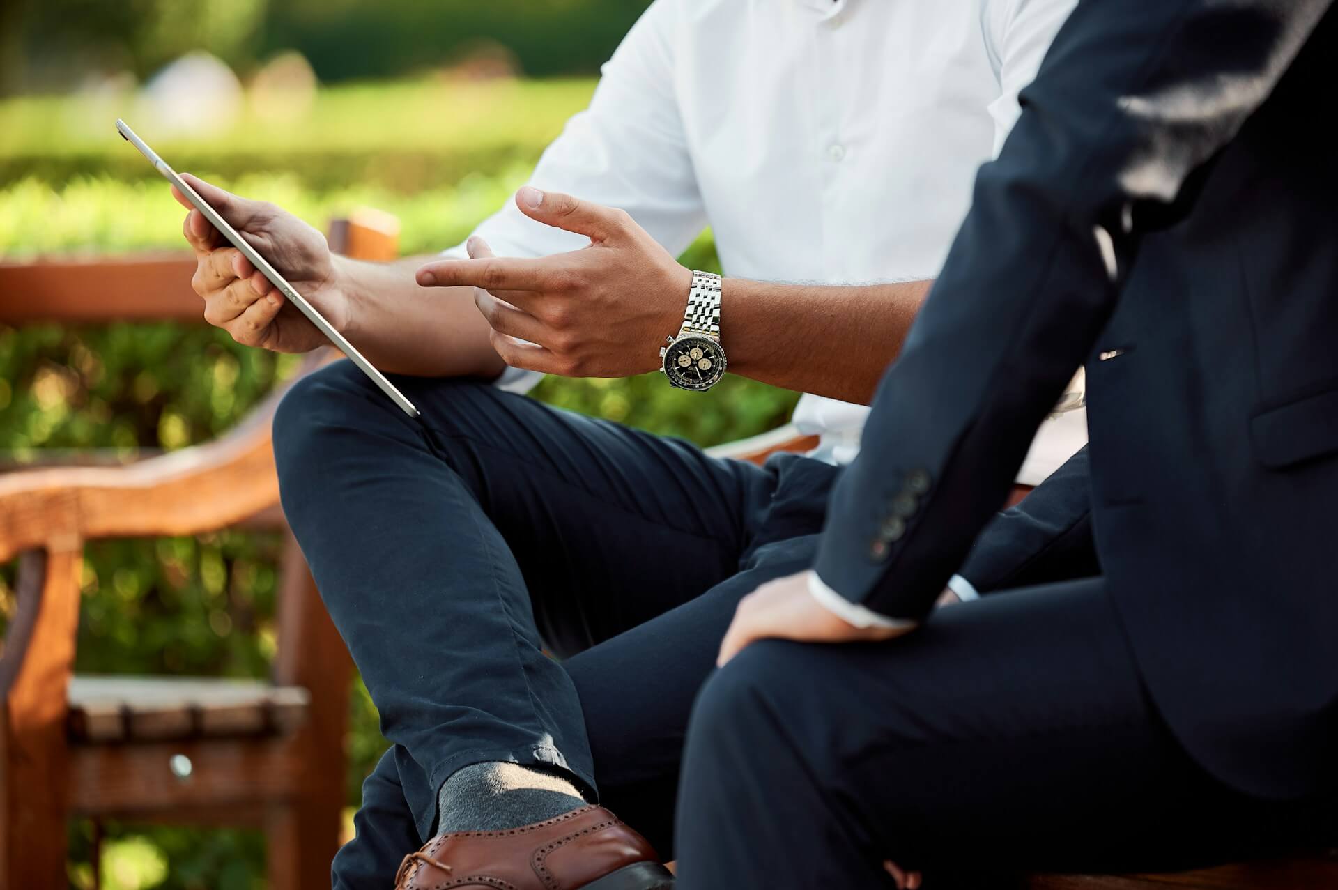 Two people sitting outside on a bench, dressed professionally, discussing goals and business