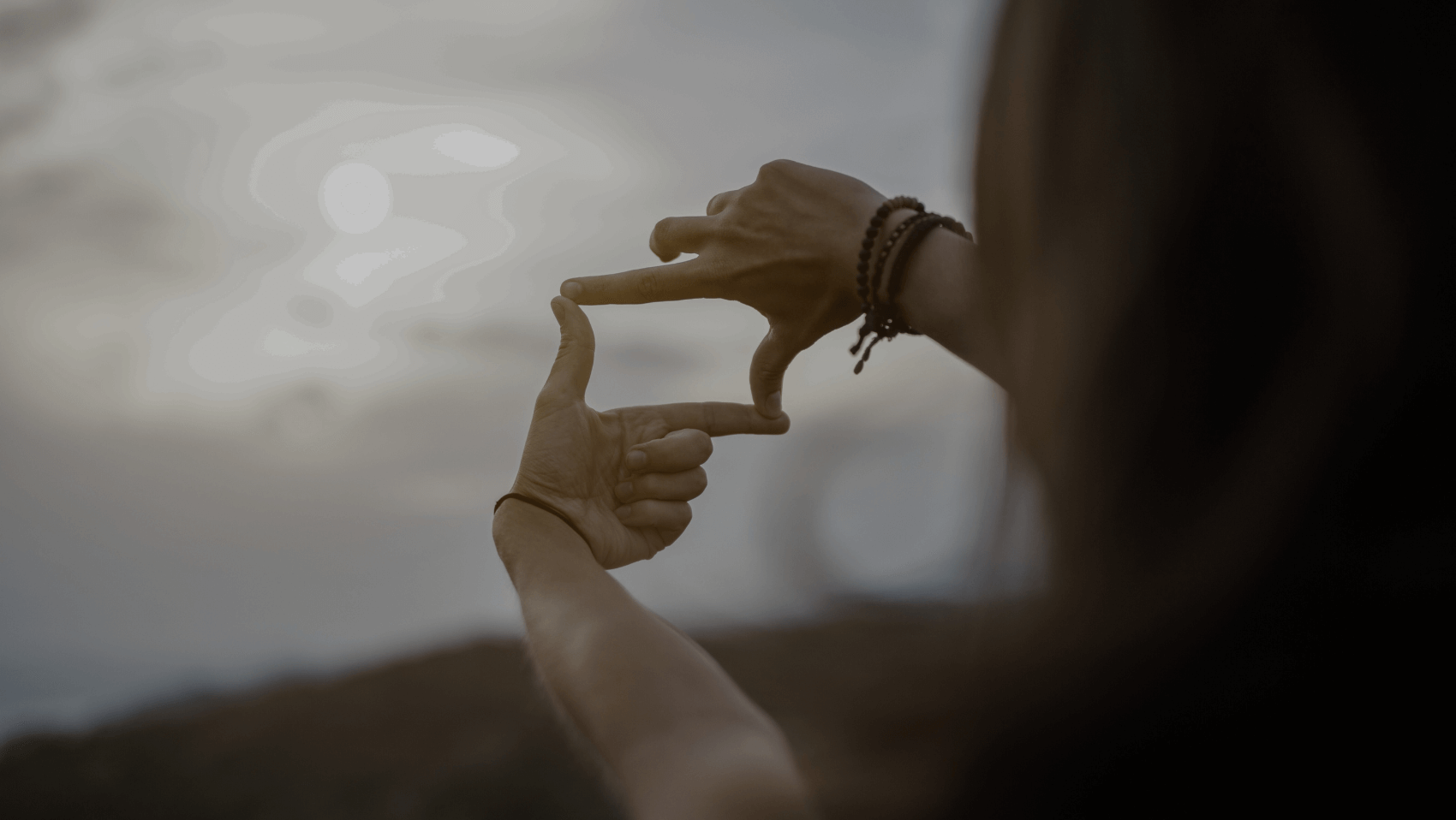 Person holding up fingers, making the "focus" film or photograph gesture