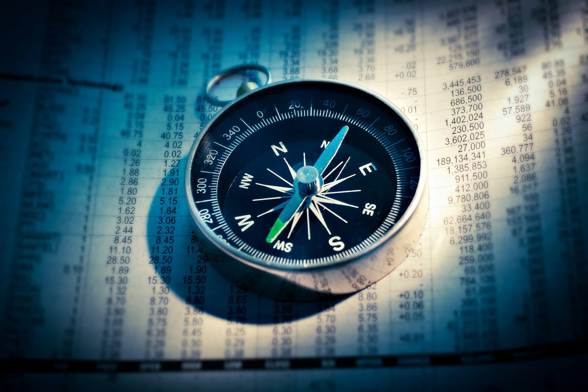 A compass sitting on top of financial documents, lit by a ray of sunlight