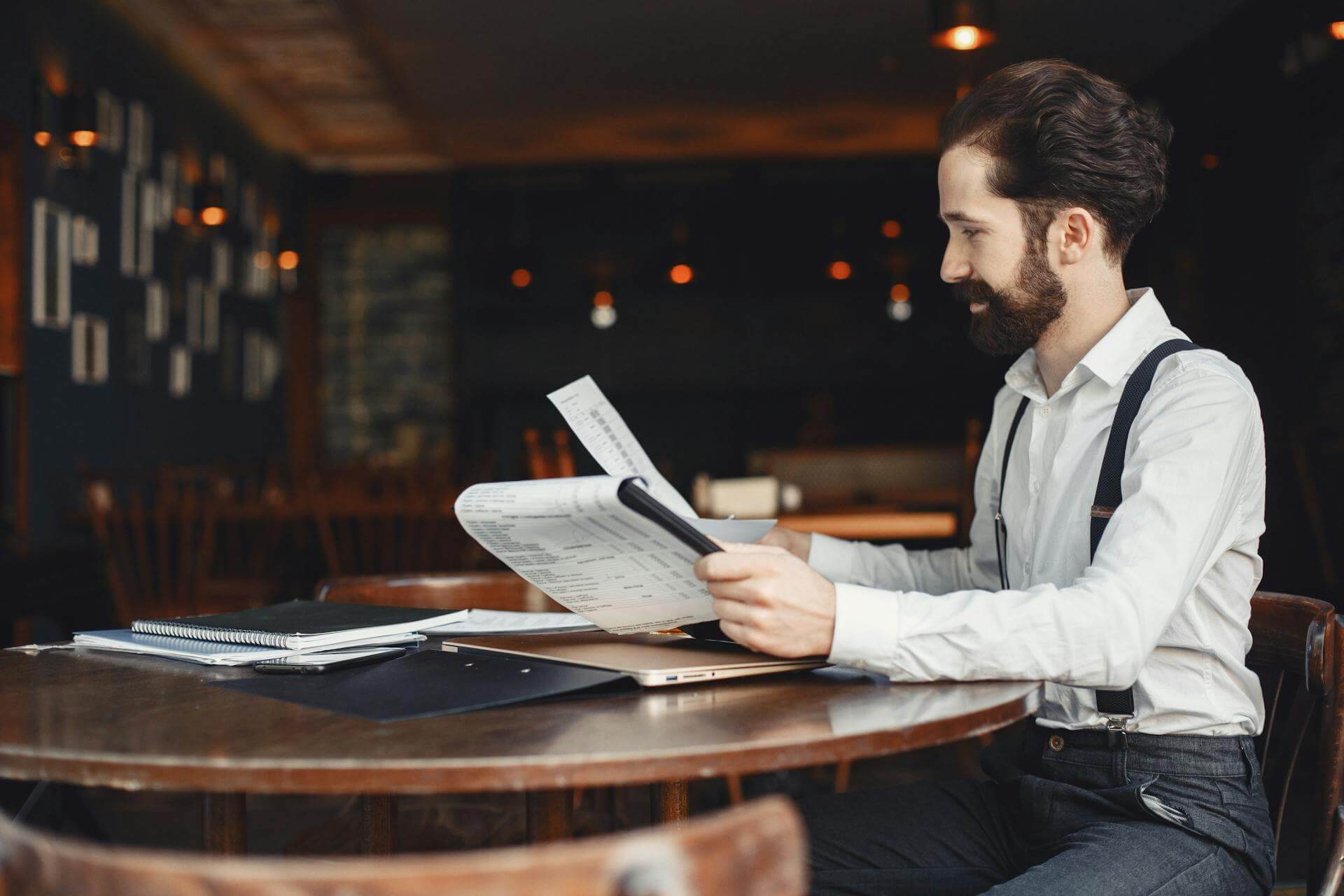 A restaurant and bar owner sitting at a table inside the business, reviewing paperwork.